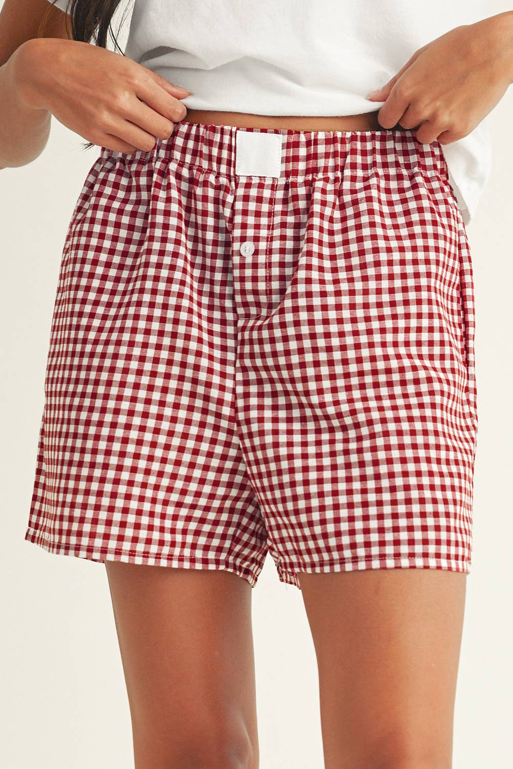 Red and white checkered shorts worn by a person on a plain background