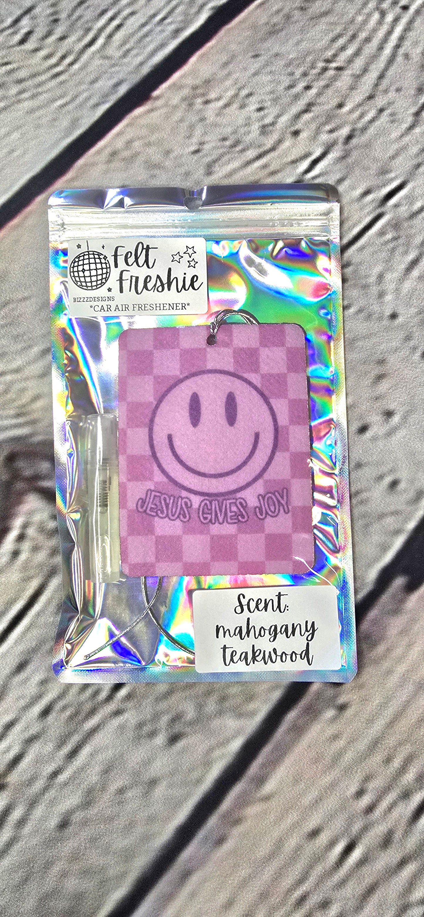 A packaged felt air freshener with a smiley face design, labeled as 'Felt Freshie'