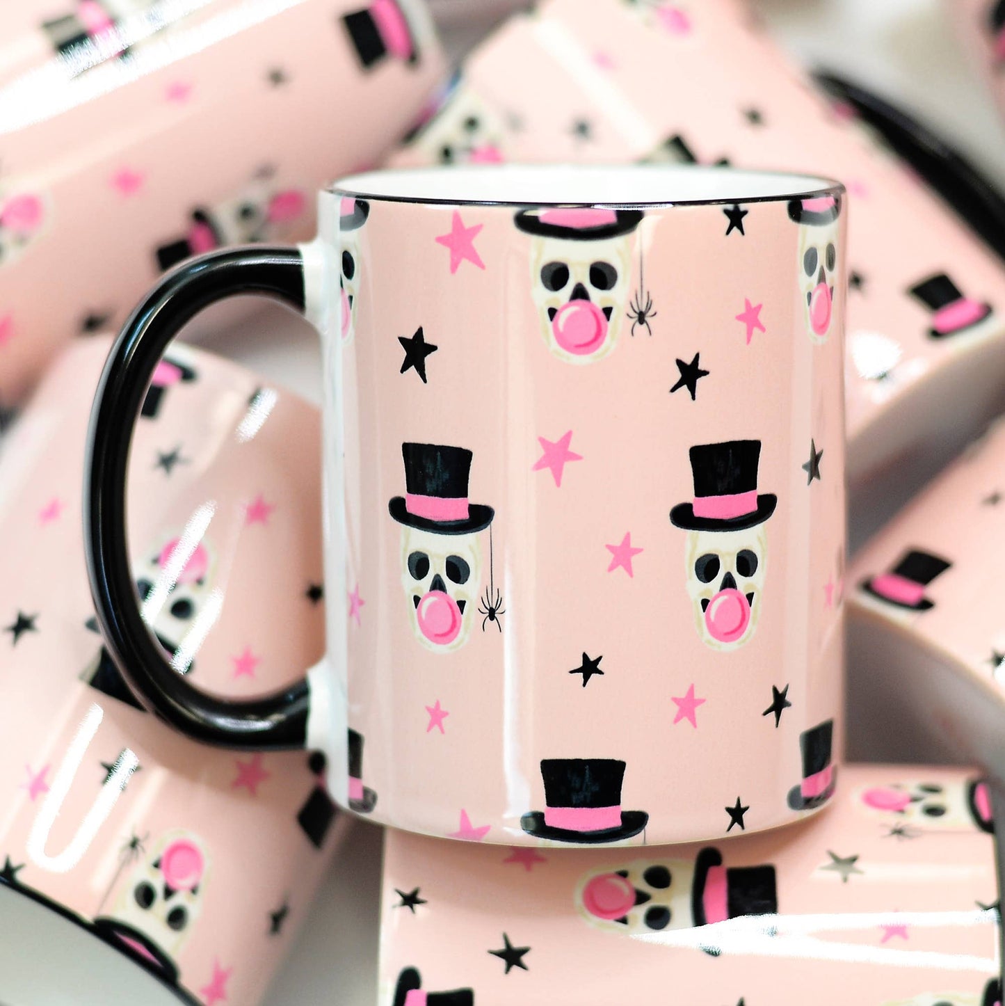Pink mug with skull and top hat design on a matching pink background
