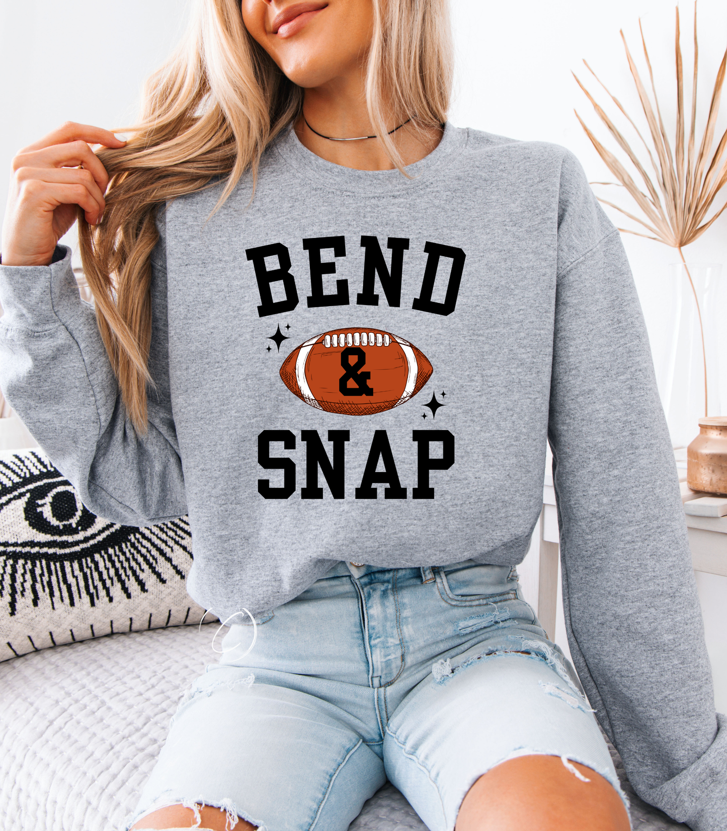 Person wearing a gray sweatshirt with 'Bend & Snap' and football graphic.