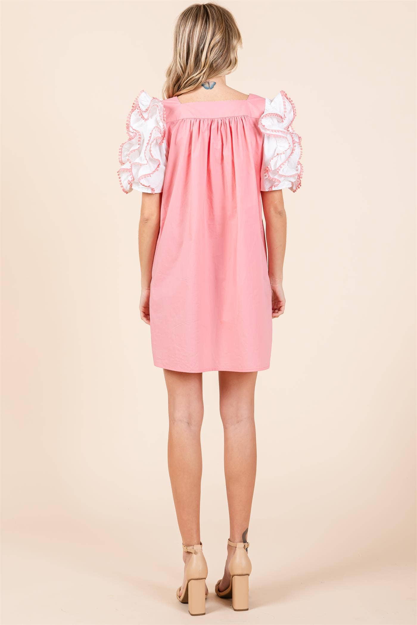 A model wearing a plus size babydoll mini dress with layered ruffled puff sleeves in a pink color.