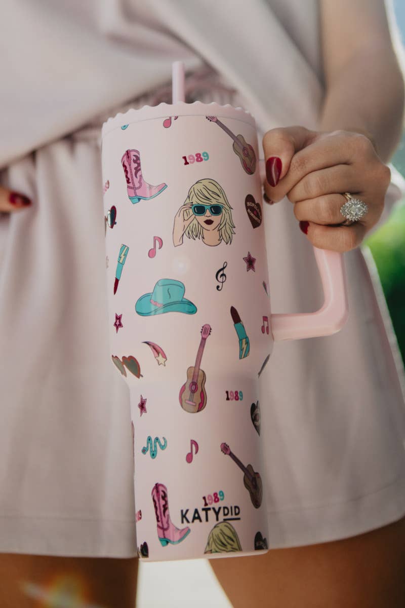 A pink 38-oz tumbler with musical icons and the brand name 'Katydid' printed on it, held in a person's hand.