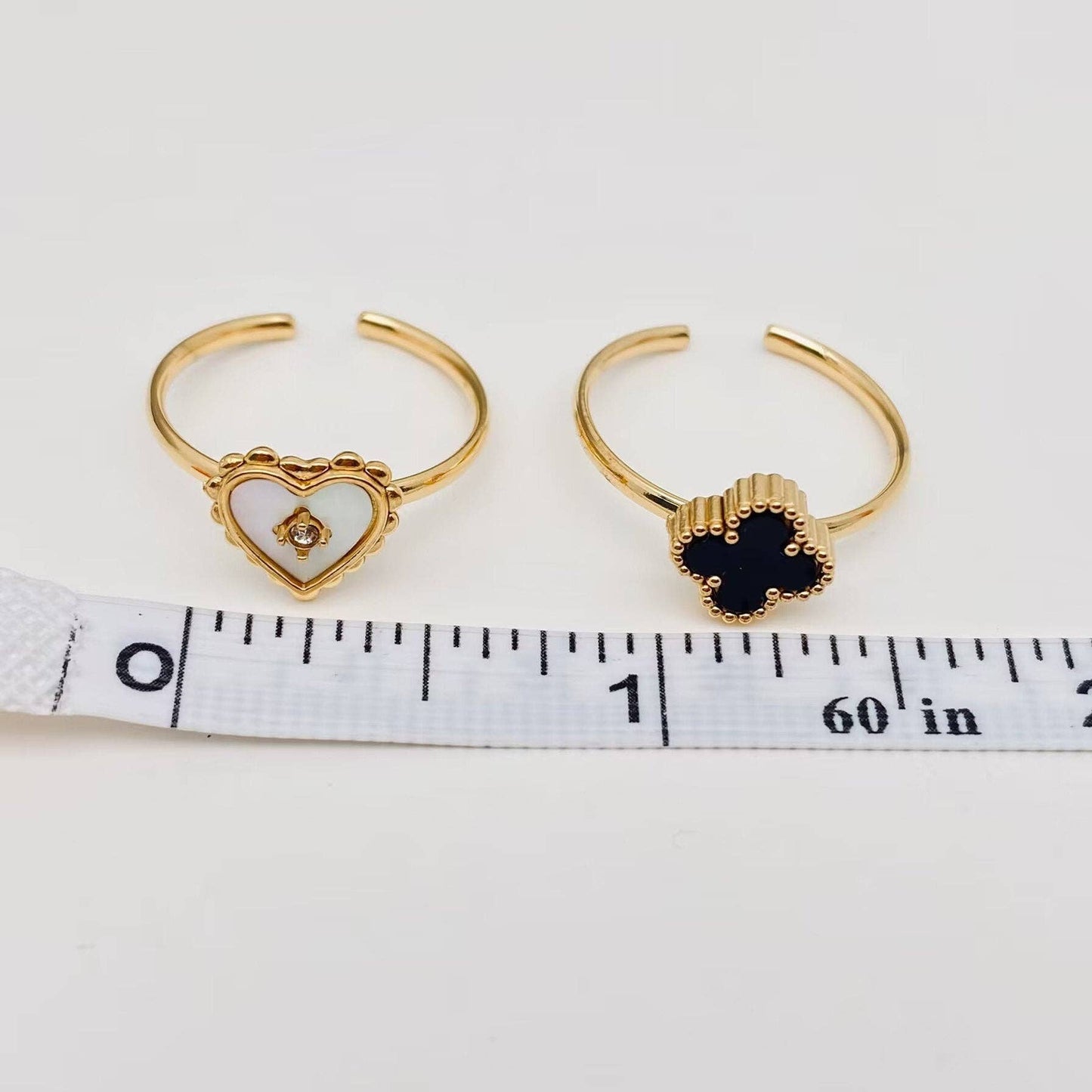 Two gold hoop earrings with heart designs on a white background with a measuring tape.
