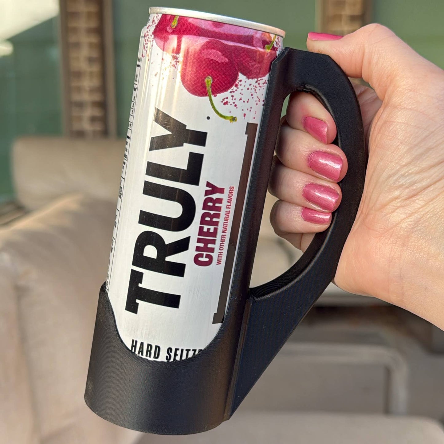 A hand holding a purple skinny can handle with a colorful can labeled 'Aloha Energy' in the background.