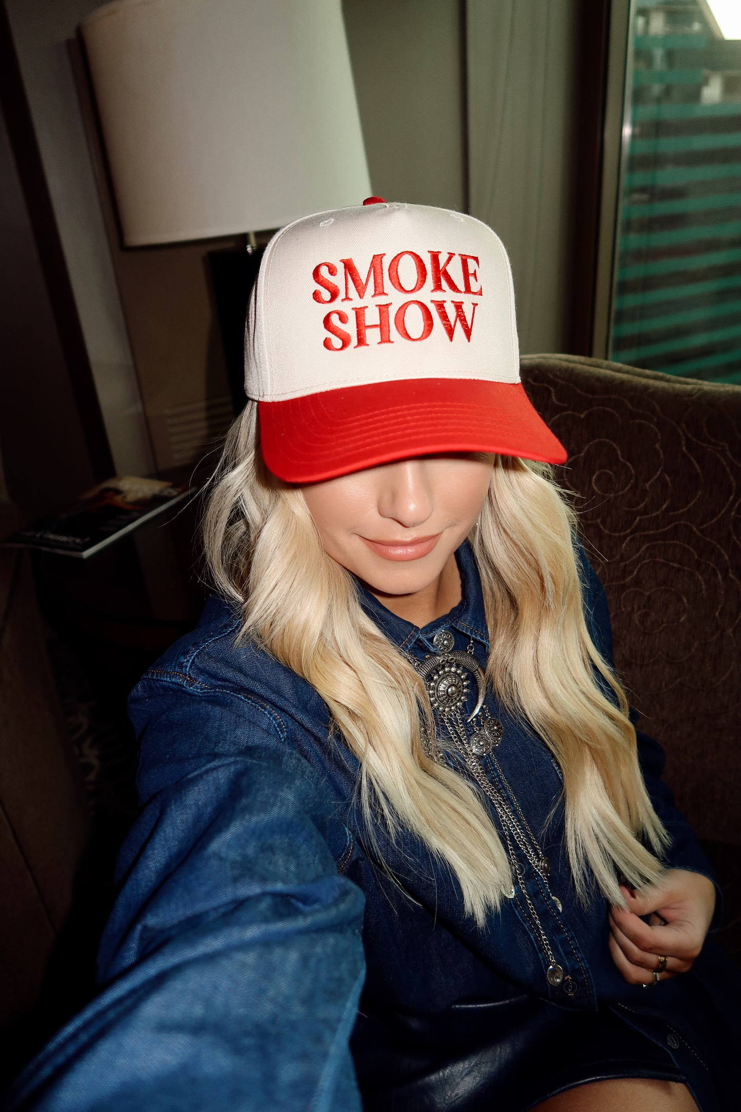A person wearing a red and white 'Smoke Show' embroidered 5-panel cap.