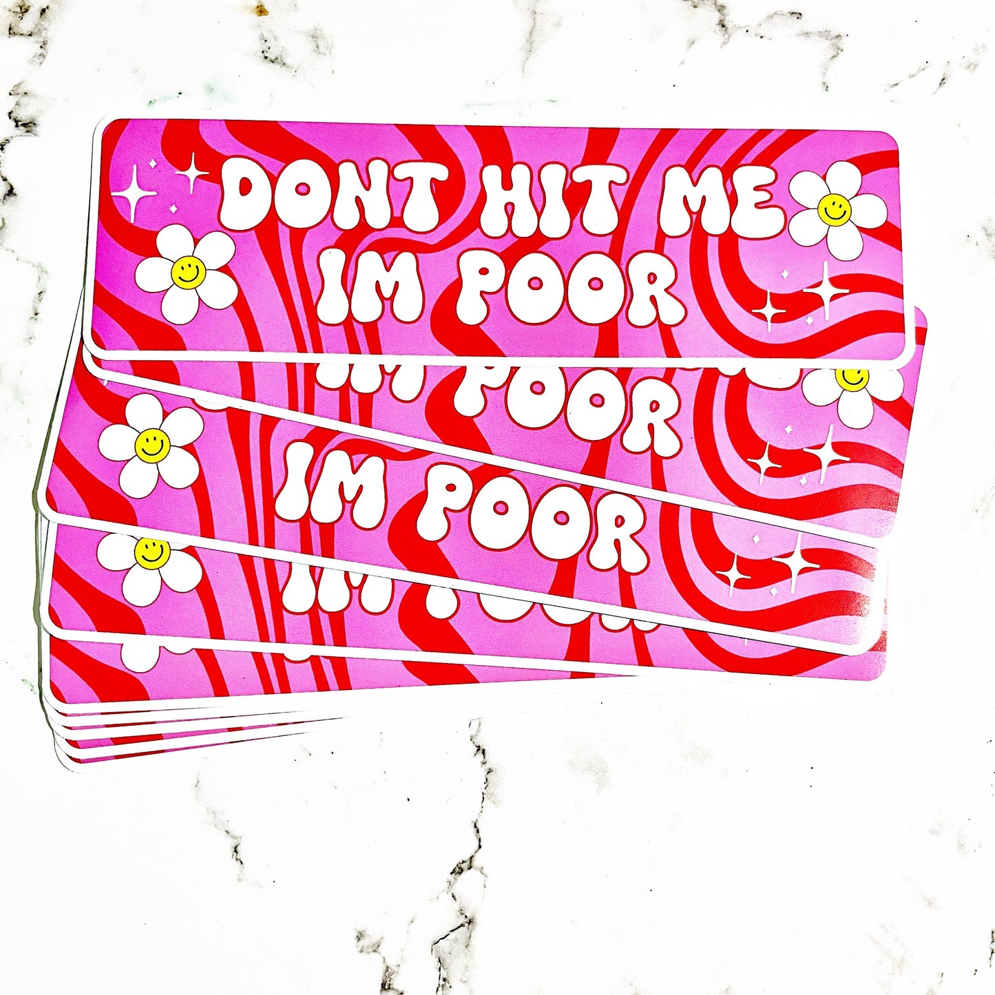 A vinyl decal with pink background and white text that reads 'DON'T HIT ME I'M POOR' repeated three times, surrounded by white stars and stripes pattern.