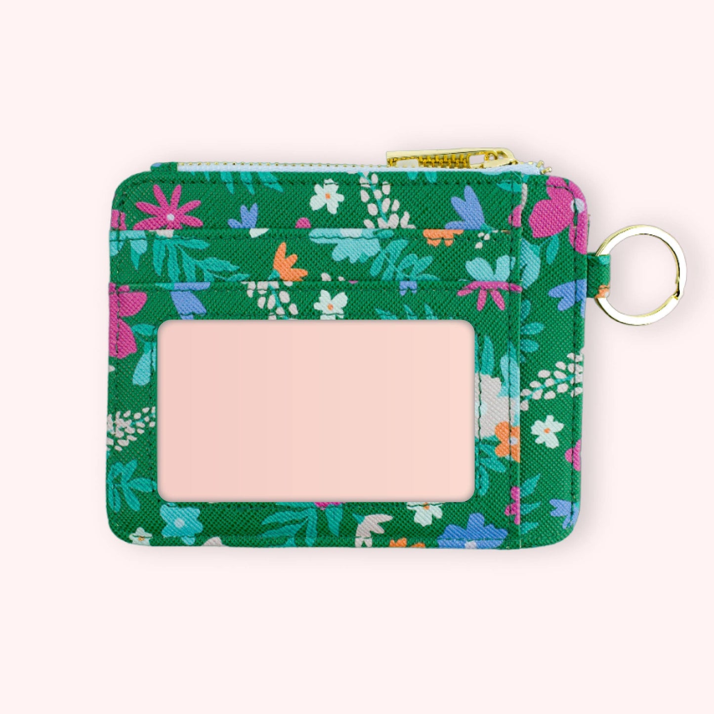 A hand holding a green wallet keychain with a floral pattern and gold hardware. The keychain is attached to a strap and there are multiple keys on it.