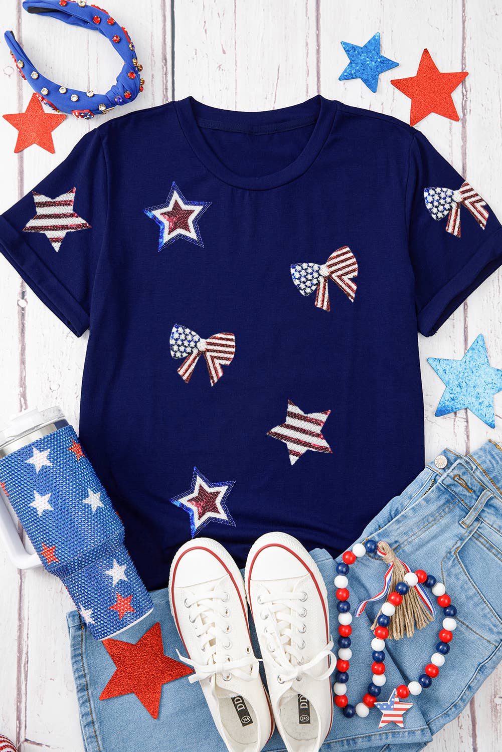 Navy blue t-shirt with American flag designs on a wooden surface with accessories.