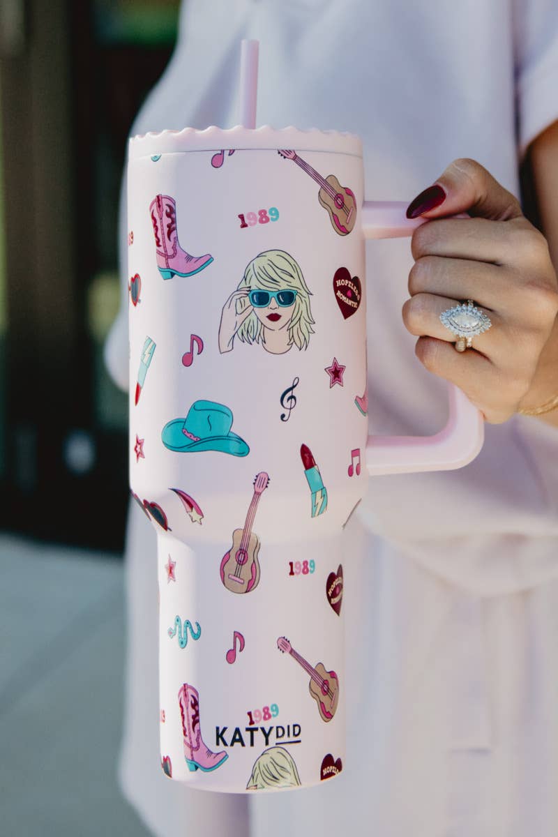 A pink 38-oz tumbler with musical icons and the brand name 'Katydid' printed on it, held in a person's hand.