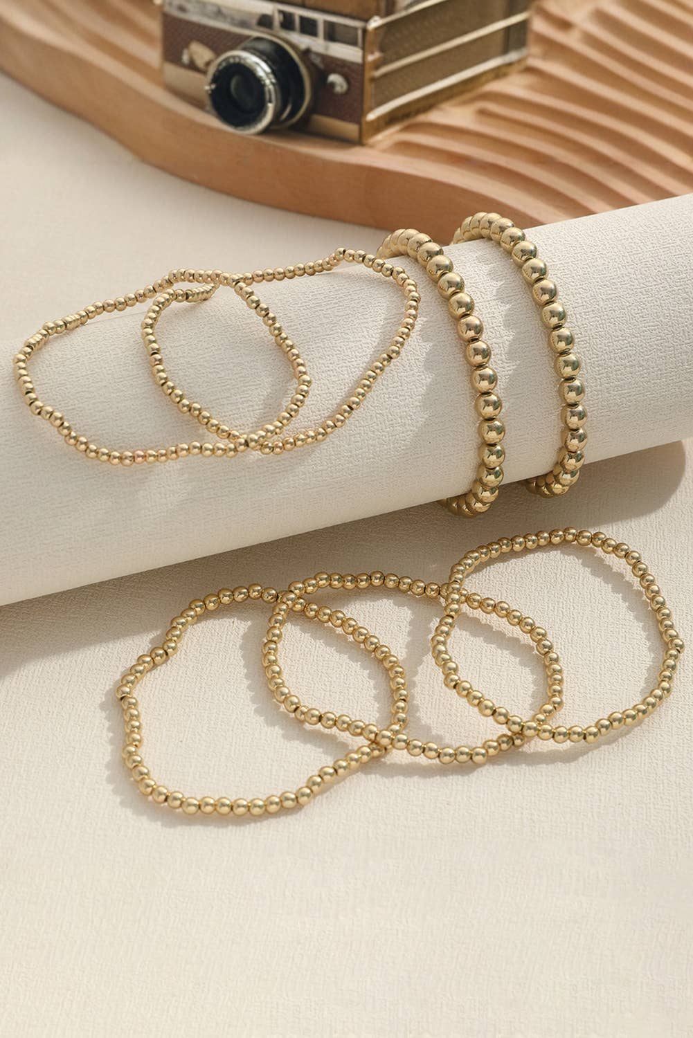 A set of seven gold-colored alloy bracelets with a beaded pattern