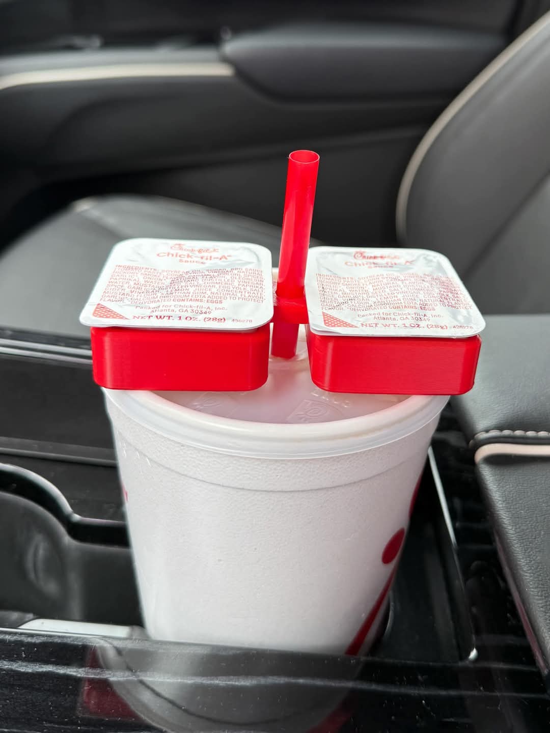 A red Saucey Dipping Sauce Holder attached to a white cup with holiday-themed designs, containing a red straw.