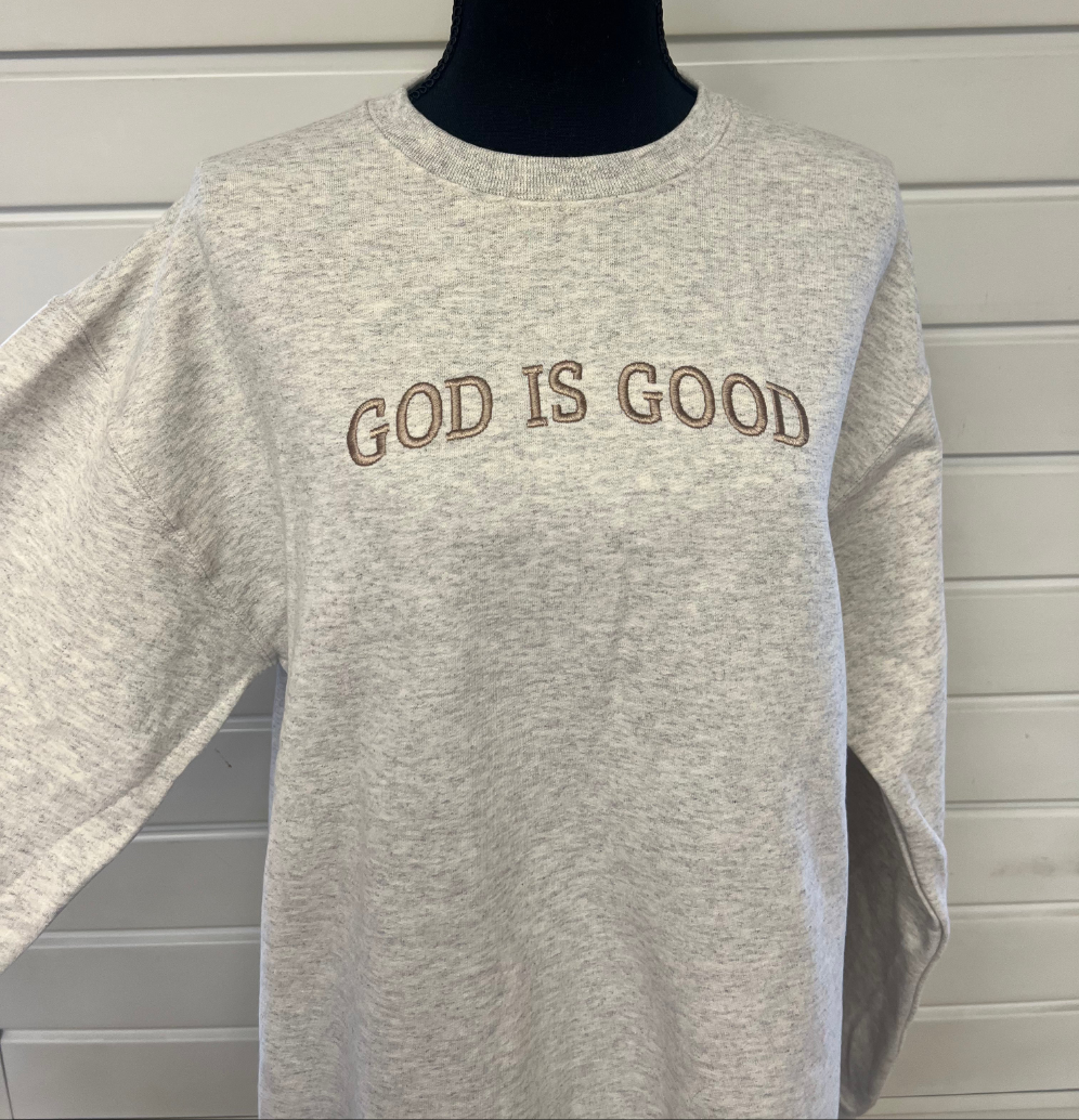 A gray sweatshirt with the phrase 'GOD IS GOOD' embroidered across the chest in capital letters.