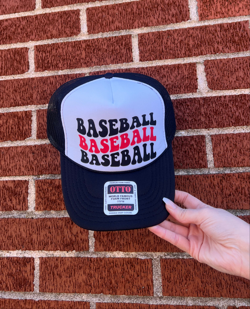 A hand holding a black and white trucker hat with 'BASEBALL' printed in bold letters on the front.