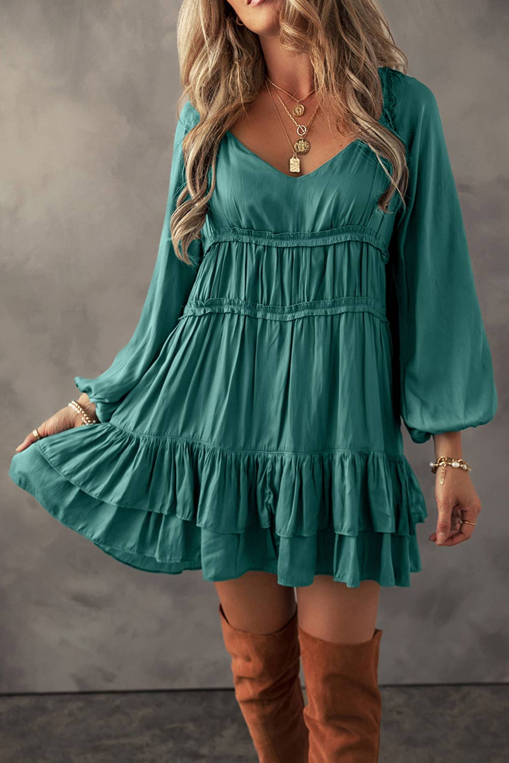 A woman wearing a green mini dress with tiered ruffles and puff sleeves, paired with brown boots.