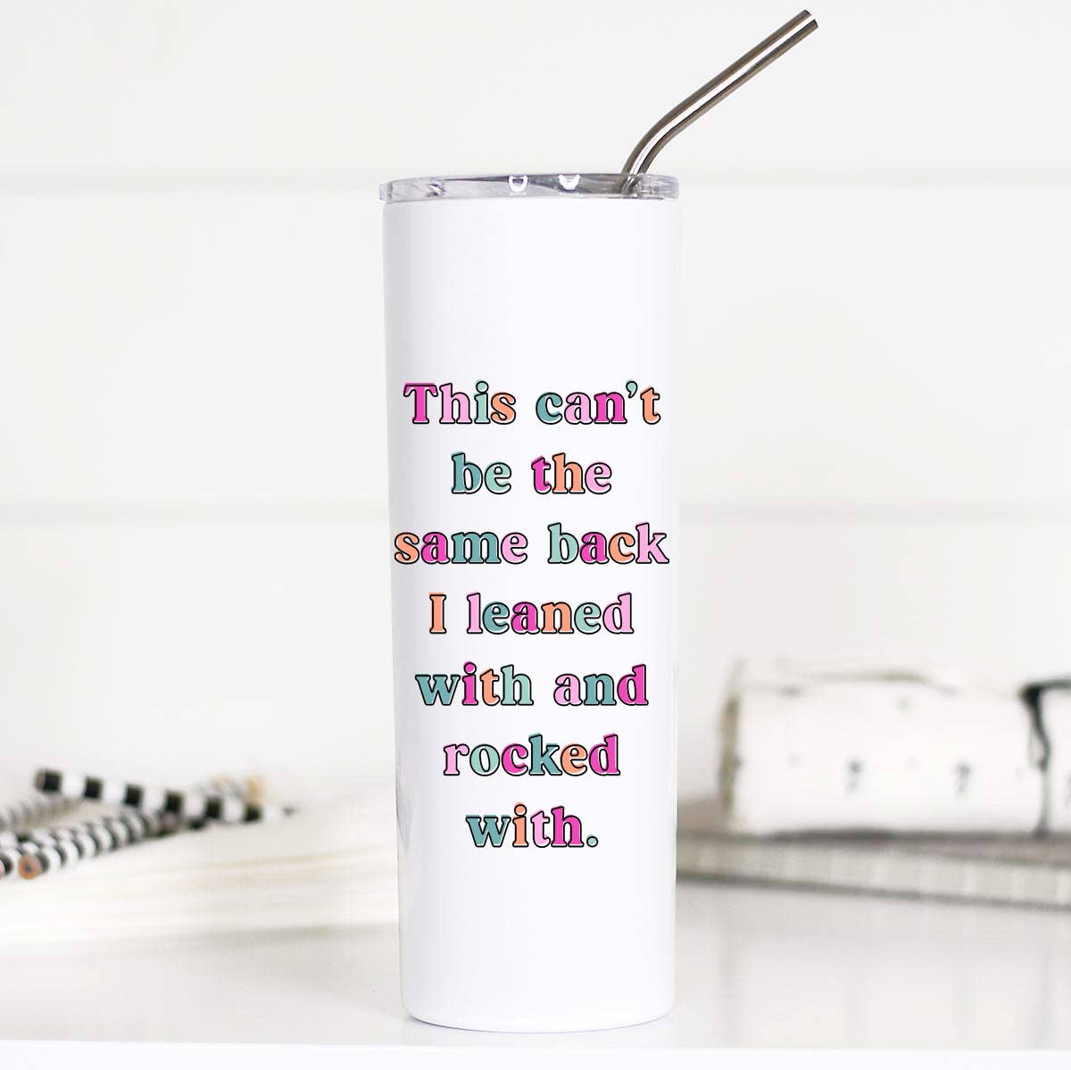 White tumbler with colorful text and a metal straw on a white background