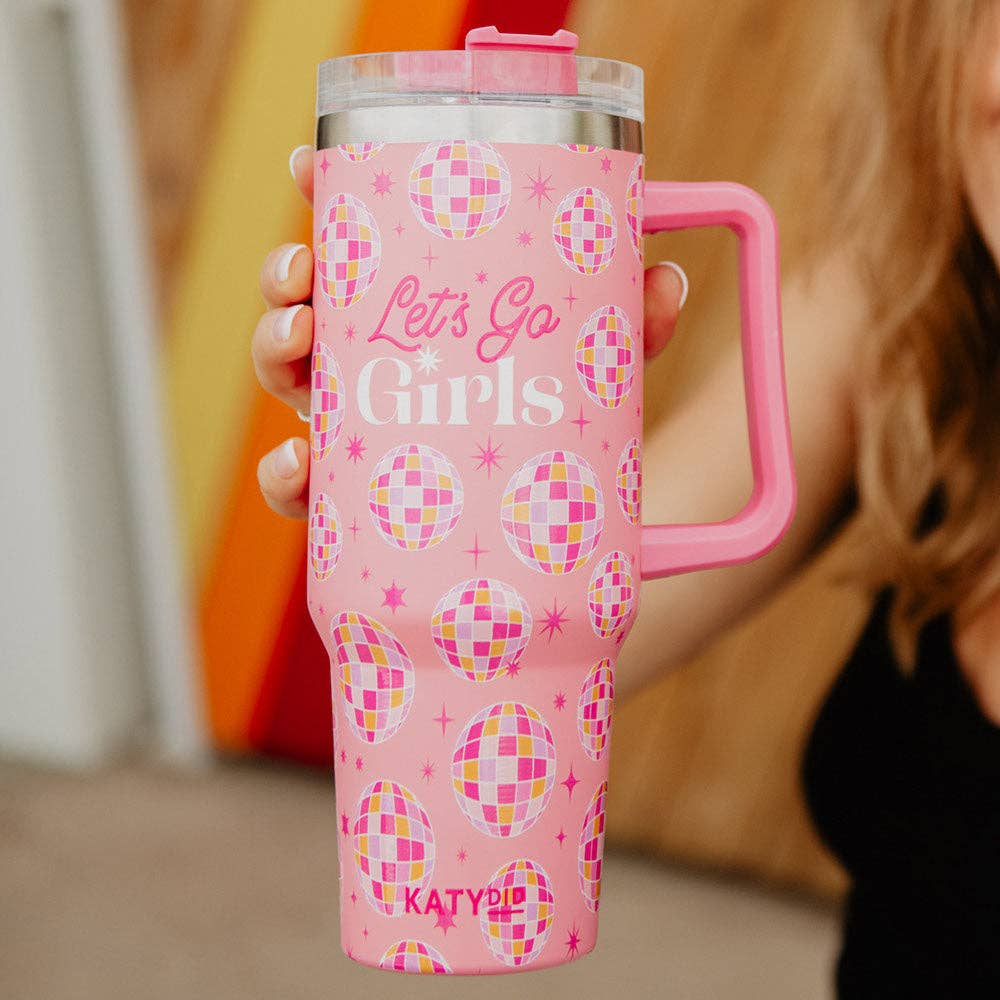 A light pink stainless steel tumbler cup with 'Let's Go Girls' text and disco ball patterns, featuring a handle and straw.