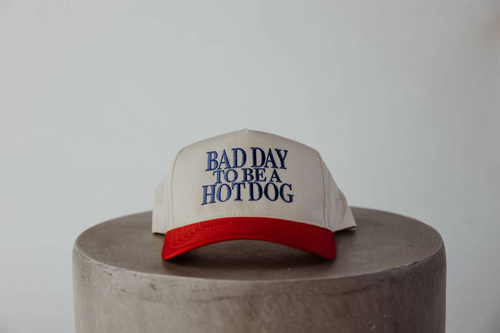 Cap with 'Bad Day to be a Hot Dog' text on a concrete surface