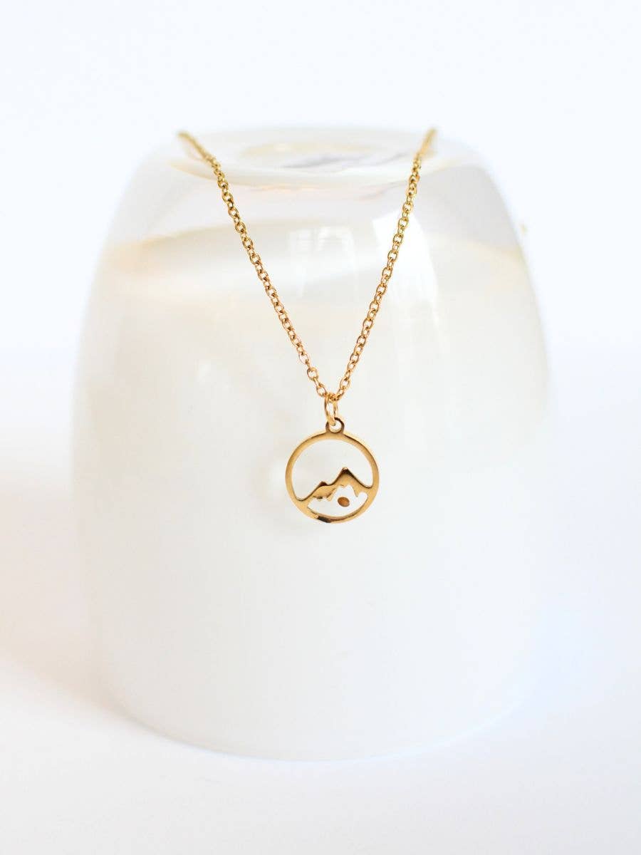 Gold necklace with a circular pendant on a white background