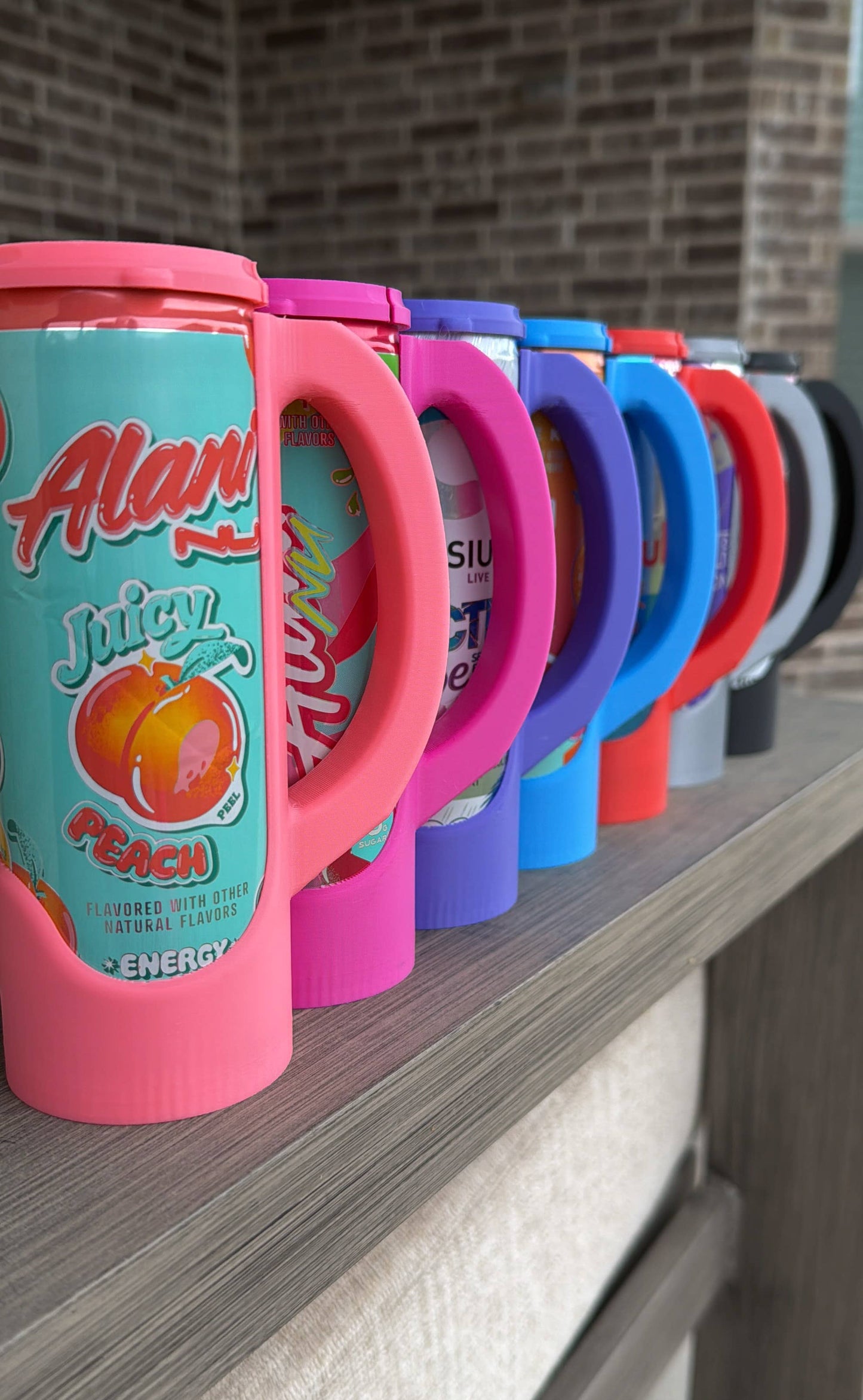 Row of colorful drink containers with visible brand names on a wooden surface.