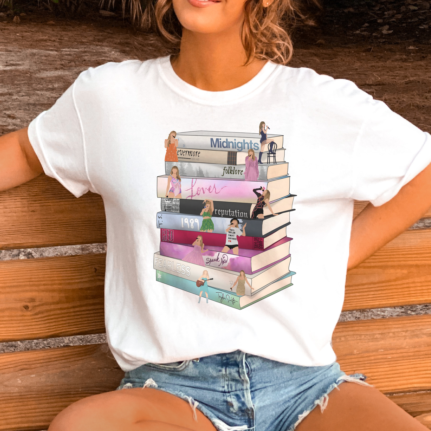 A graphic tee with a stack of books print, each representing an album by Taylor Swift.
