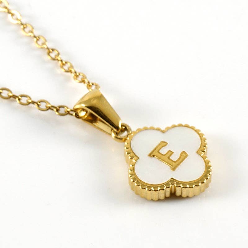 Gold necklace with a clover-shaped pendant featuring the letter 'E' on a white background