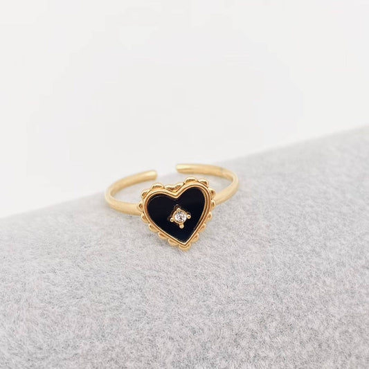 Gold ring with a black heart-shaped stone on a light gray surface