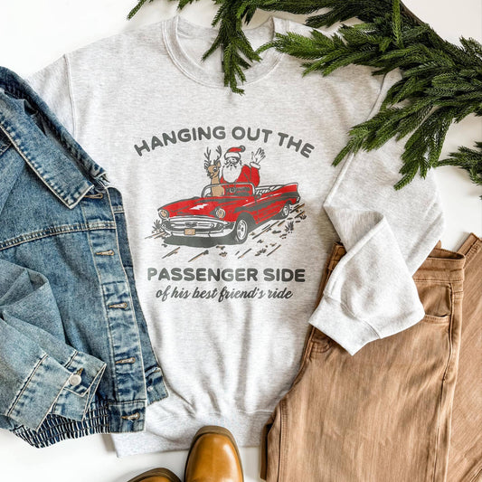 gray sweatshirt with Christmas design featuring Santa and a car, surrounded by denim jacket and brown pants on a white background.