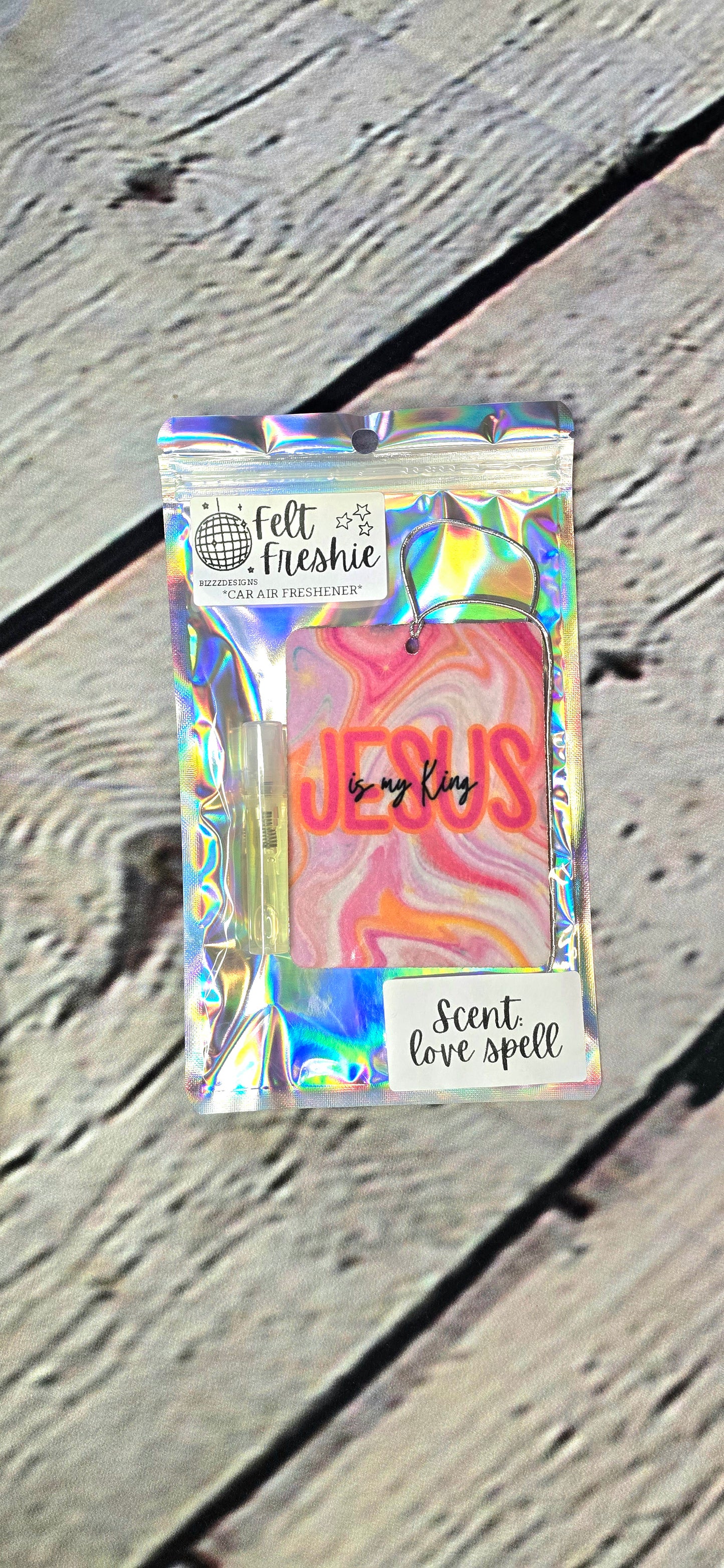 A felt air freshener with a multicolored design and the text 'JESUS IS MY KING' along with the brand name 'Felt Freshie'. 