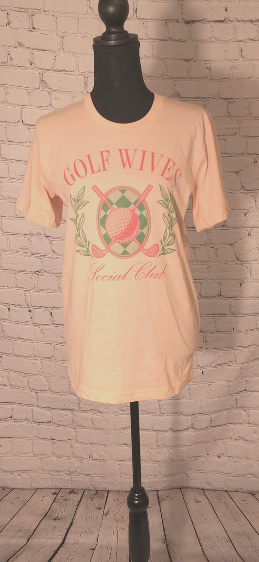 A pink-colored crew neck t-shirt with the text 'GOLF WIFE' and a graphic print related to golfing, displayed on a mannequin.