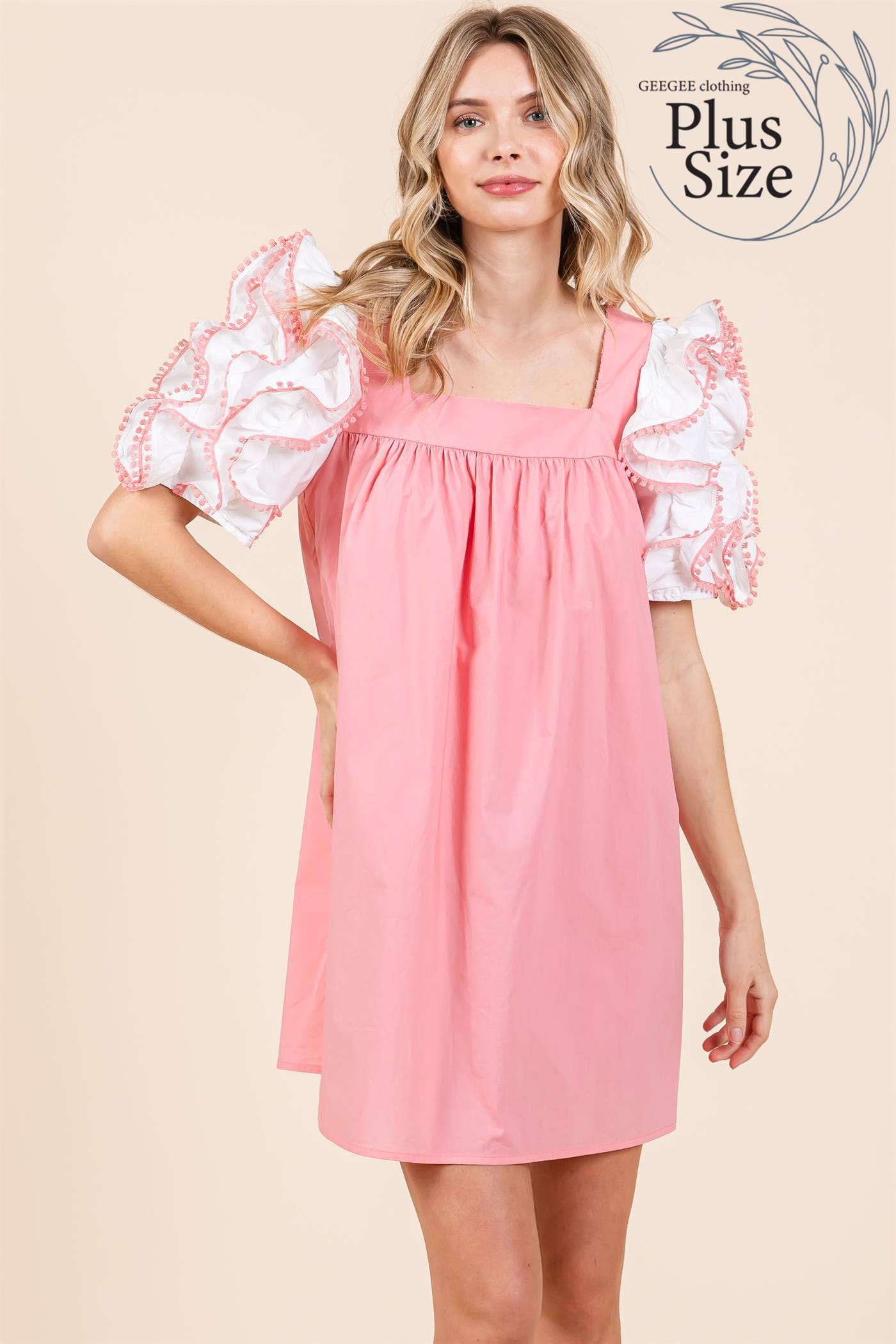 A model wearing a plus size babydoll mini dress with layered ruffled puff sleeves in a pink color.