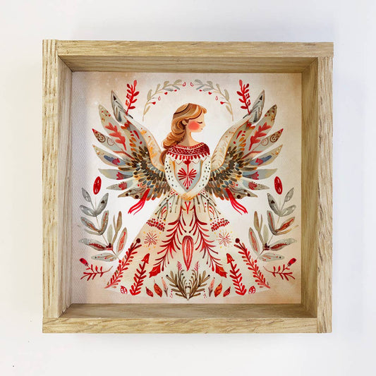 Framed artwork of a woman with angel wings and floral patterns on a white background