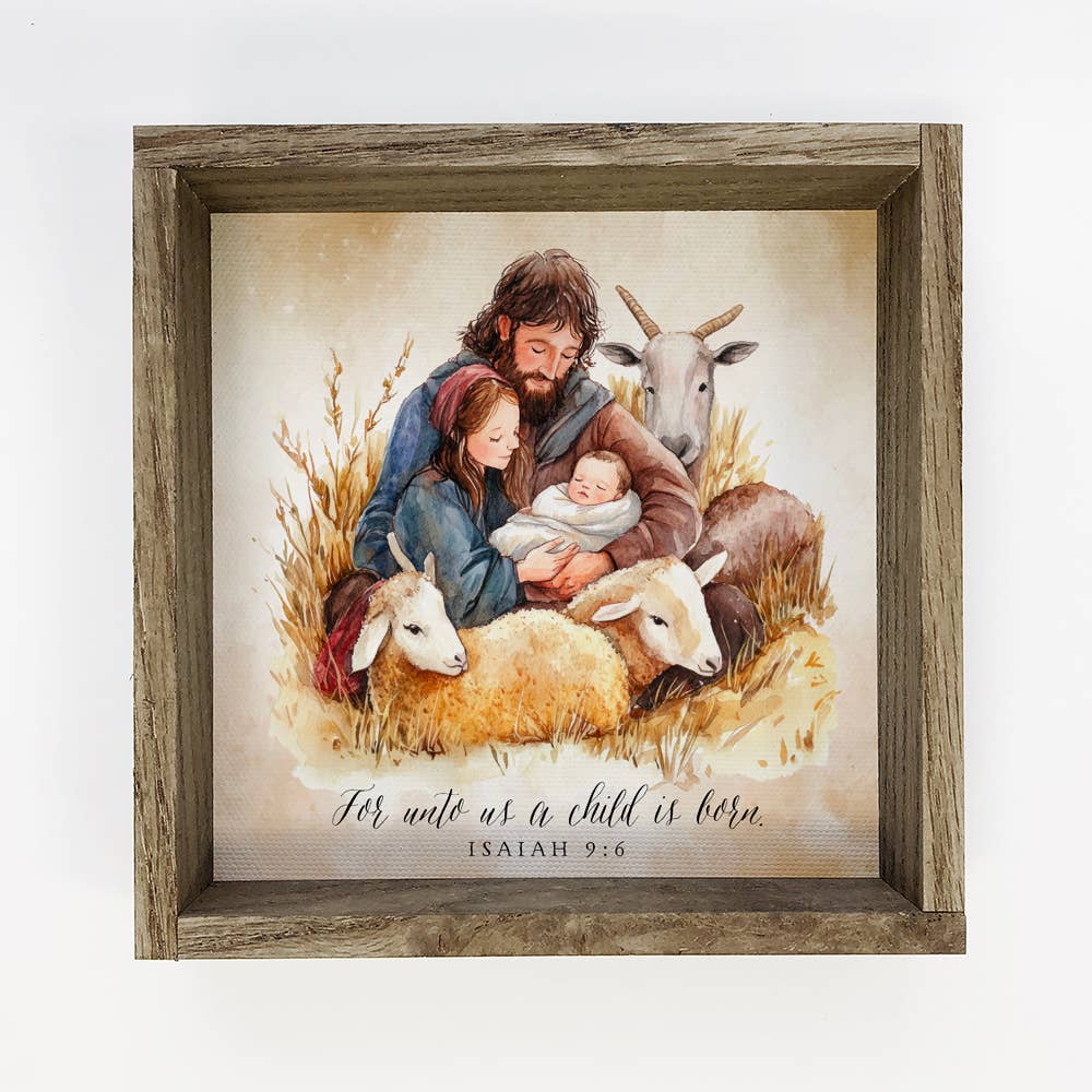 Framed artwork of a man, woman, and child with sheep and a goat, featuring the text 'For unto us a child is born.' from Isaiah 9:6.