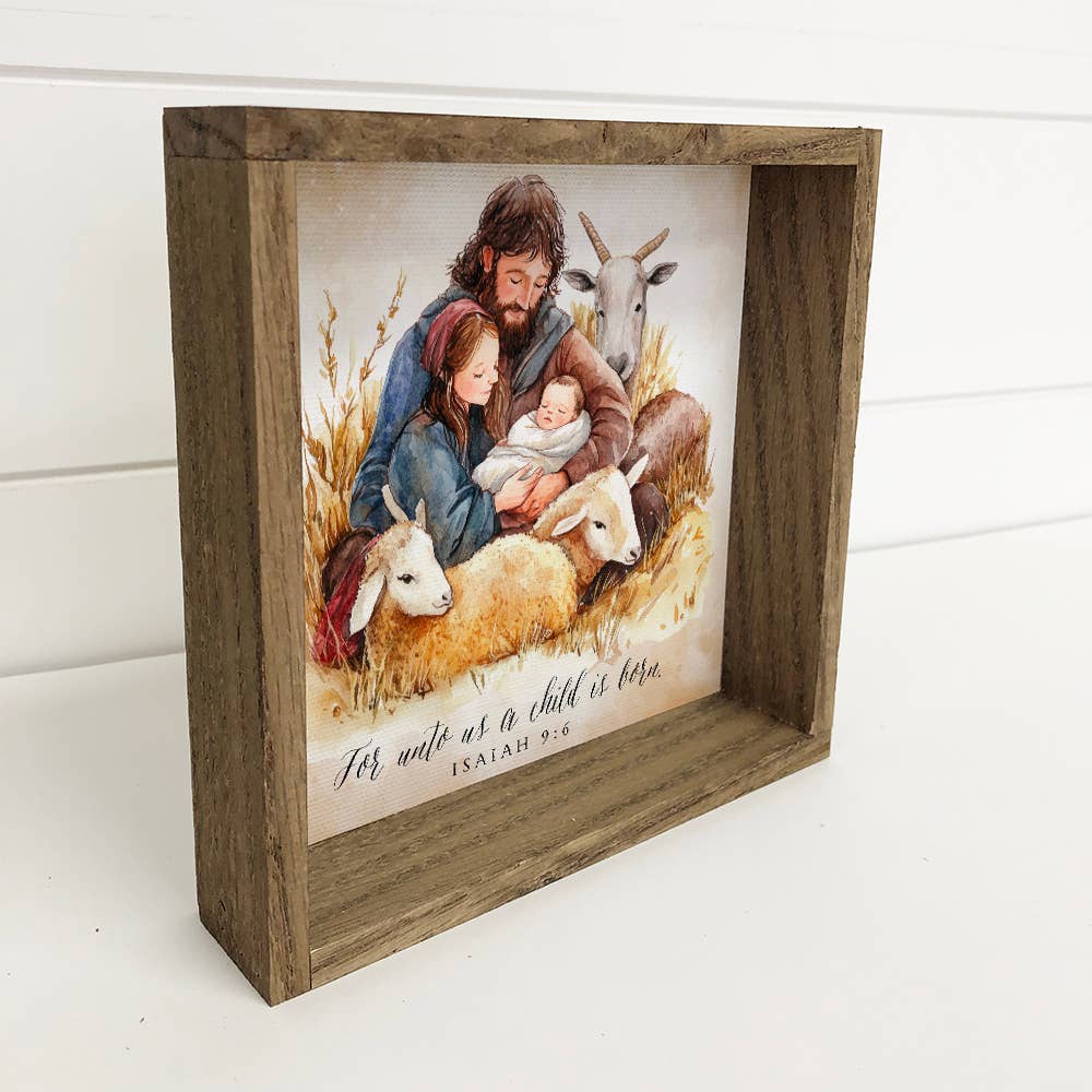 Wooden framed artwork with a depiction of a man, woman, and child surrounded by sheep, on a white background.