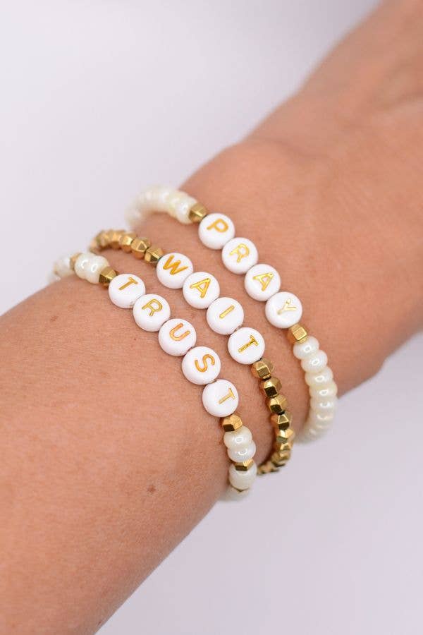 Bracelets with letter beads on a wrist against a white background