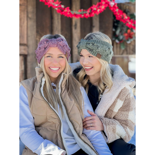 Two women wearing knitted headbands in a snowy outdoor setting.
