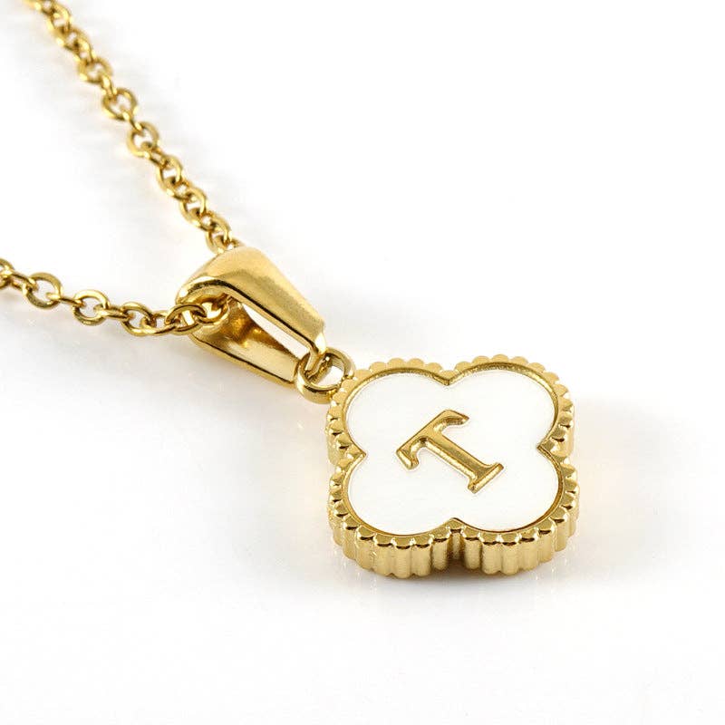 Gold necklace with a clover-shaped pendant featuring the letter 'T' on a white background