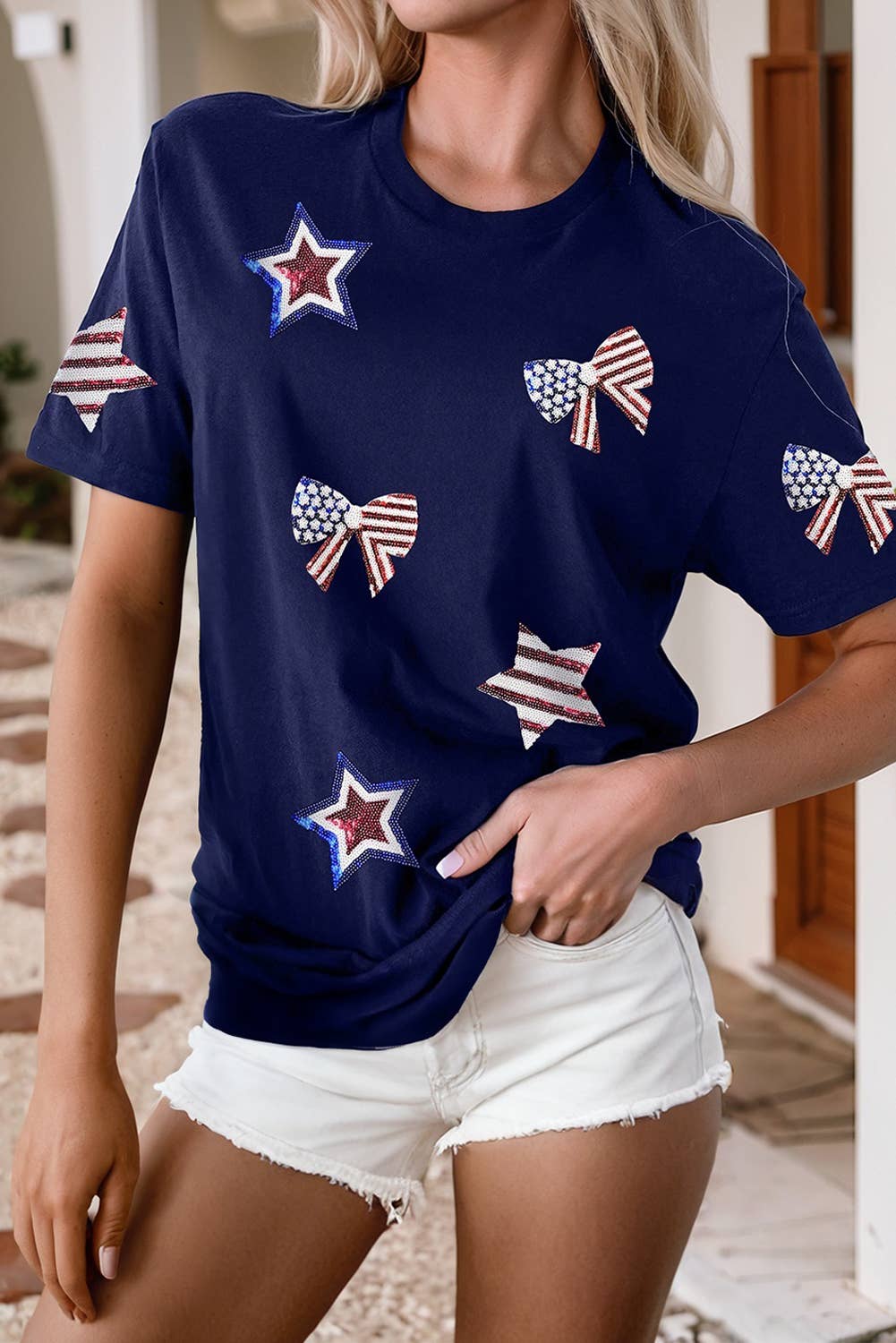 Person wearing a navy blue t-shirt with star and bow designs, standing indoors.