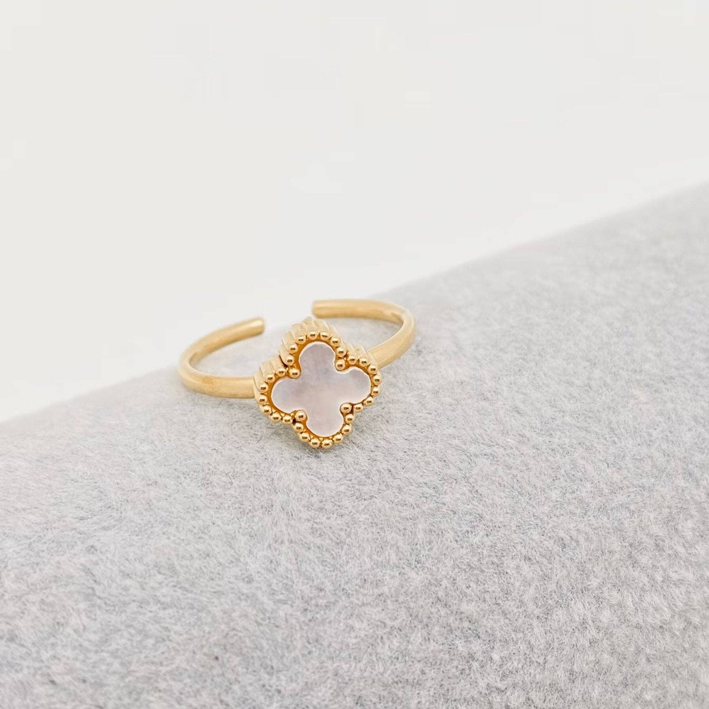 Gold ring with a clover-shaped center on a light gray background