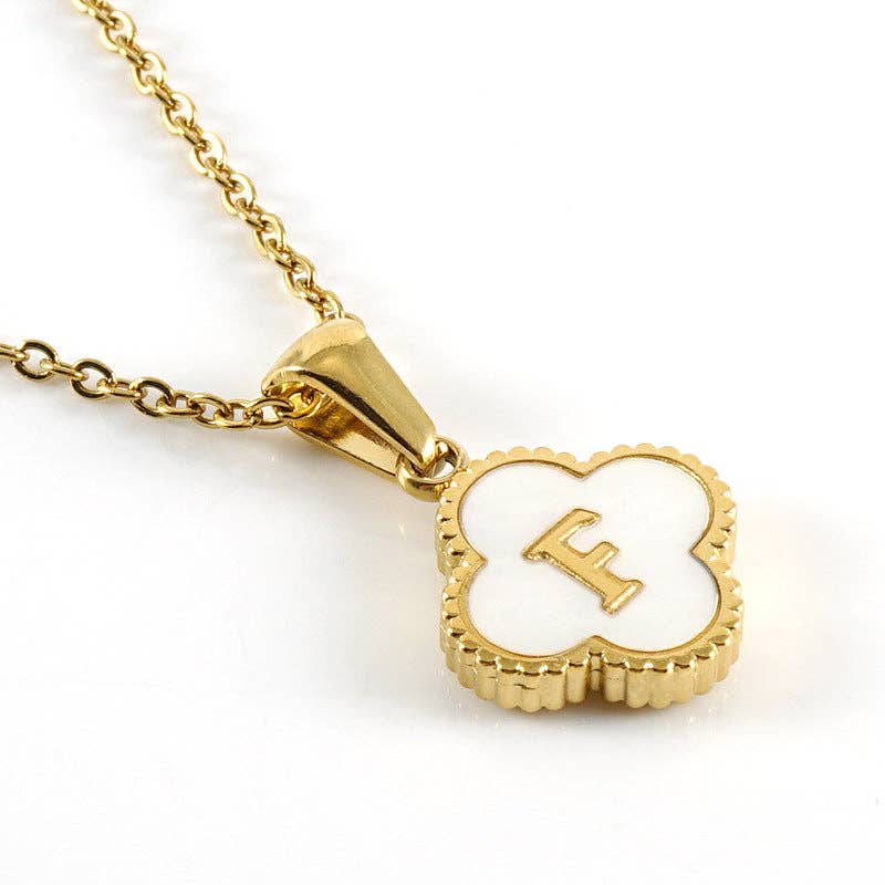 Gold necklace with a clover-shaped pendant featuring the letter 'F' on a white background