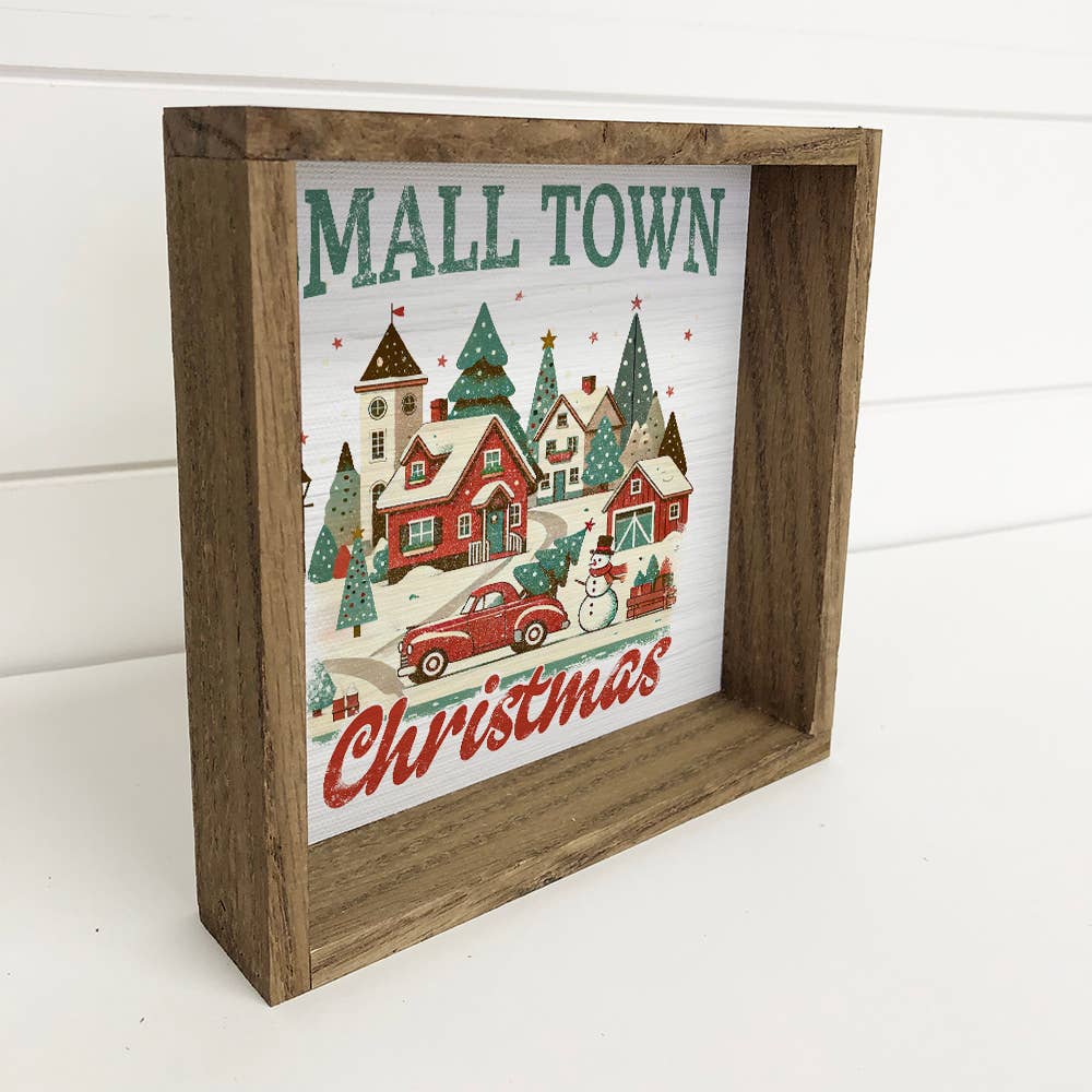 Wooden framed Christmas-themed sign with a festive village illustration.