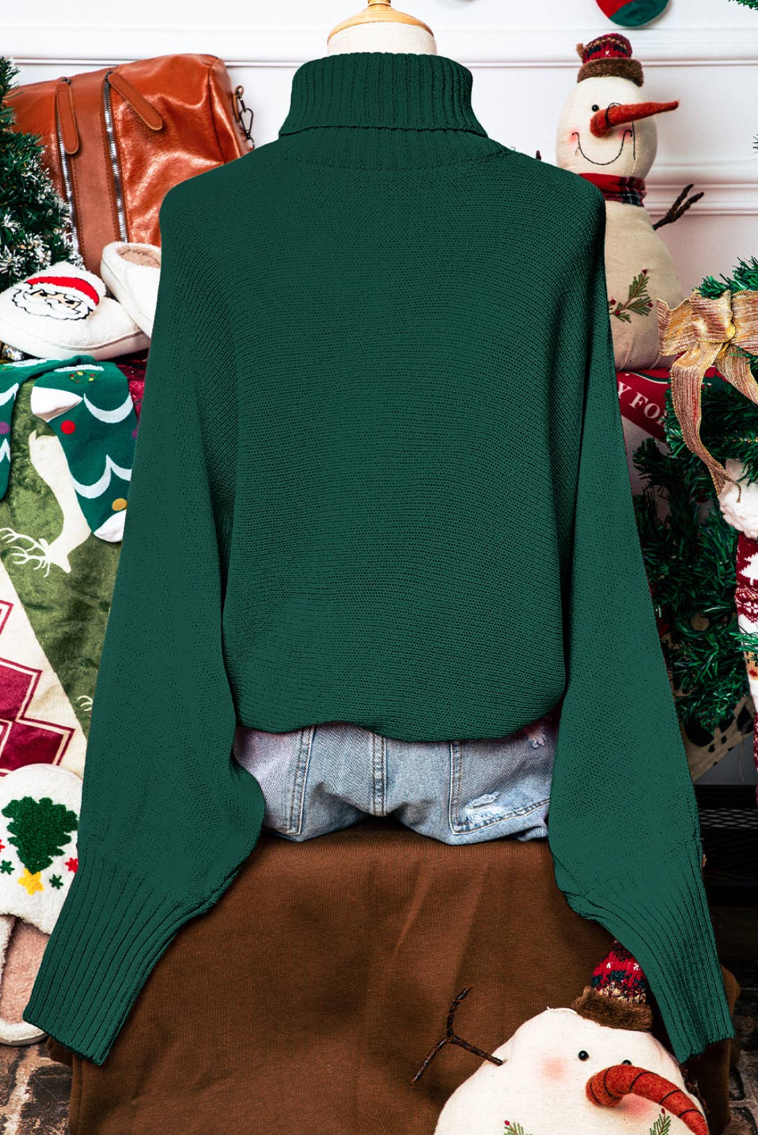 Green sweater on a mannequin with a festive background featuring Christmas decorations.