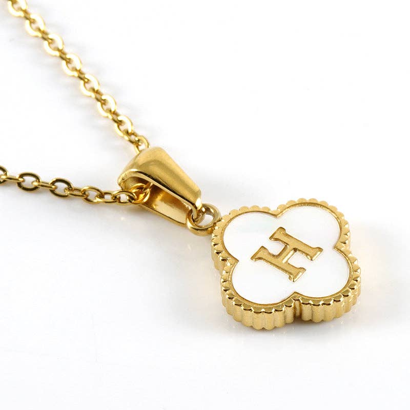 Gold necklace with a clover-shaped pendant featuring the letter 'H' on a white background