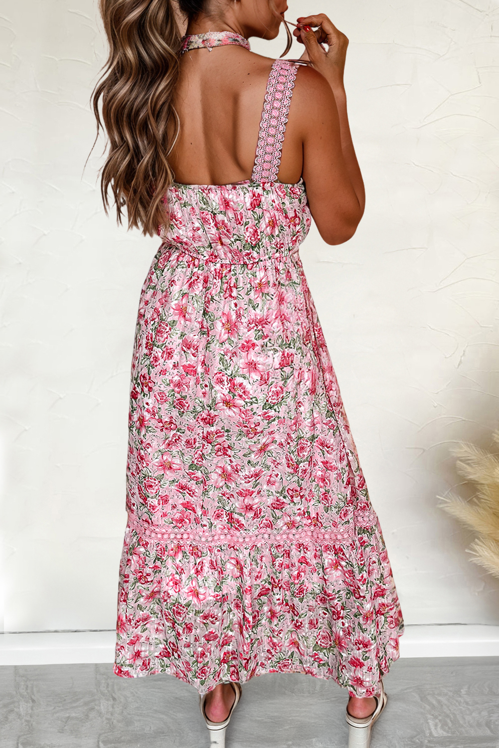 A woman wearing a floral lace tied strap empire waist maxi dress in pink.