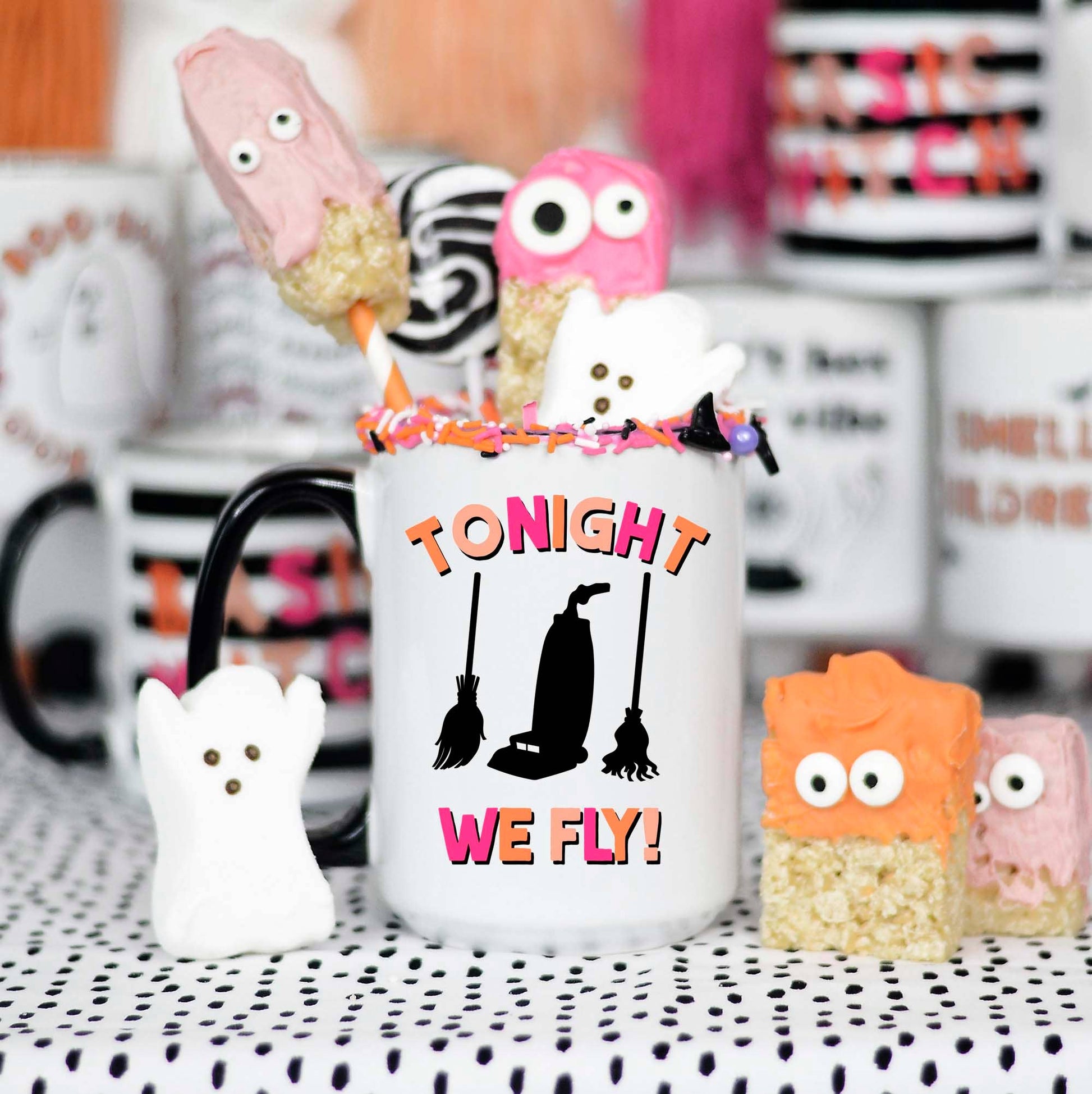 Halloween-themed mug with decorative treats on a polka dot tablecloth.