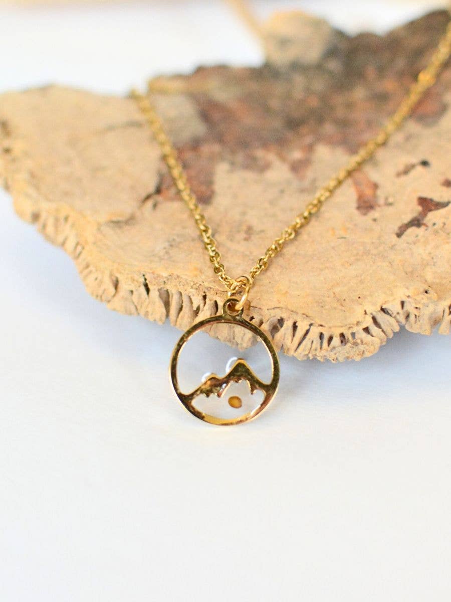 Gold necklace with a circular pendant on a textured surface