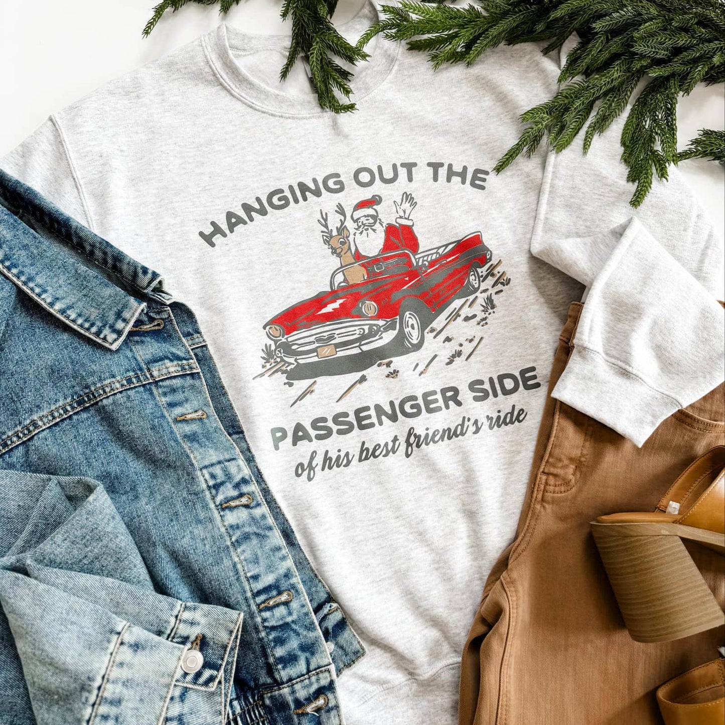 gray t-shirt with Santa Claus graphic and text, surrounded by denim jacket and brown shoes.
