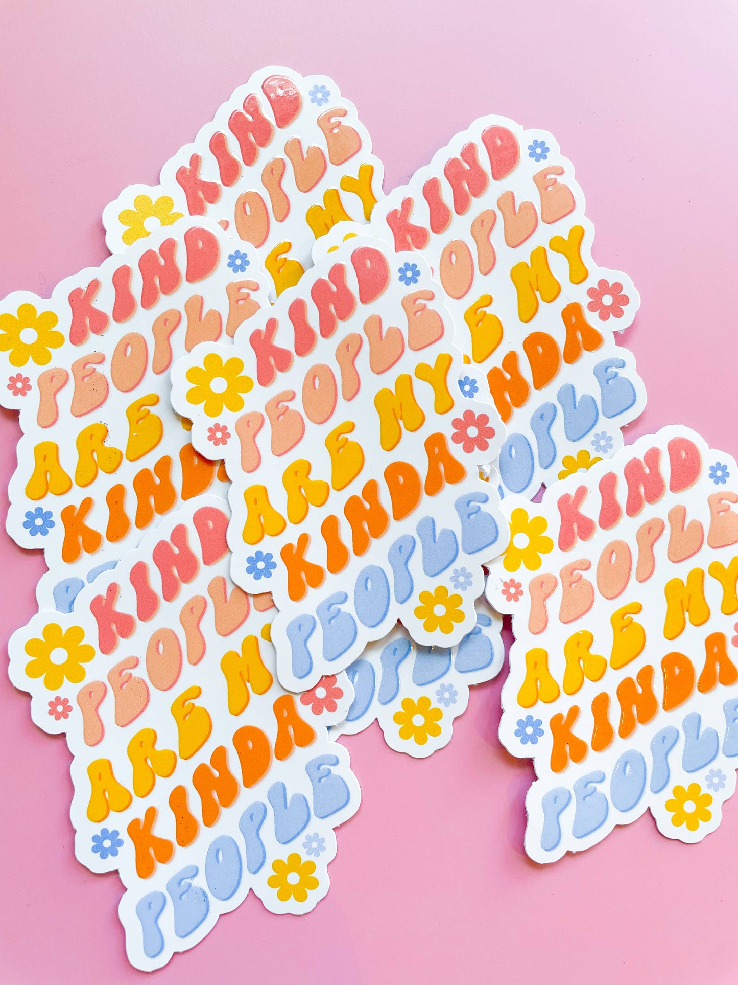 Stickers with the phrase 'Kind People are my Kinda People' printed in various colors, placed on a pink background.