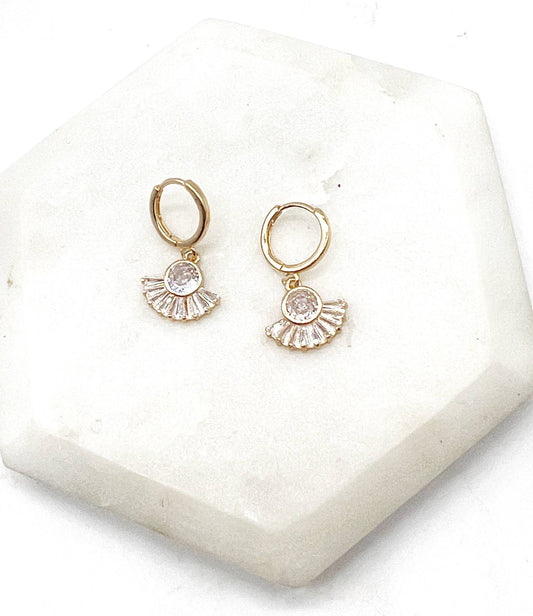 Gold hoop earrings with a central gemstone on a white stone surface