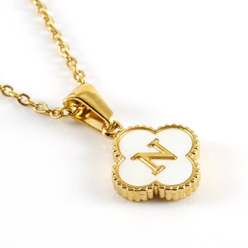 Gold necklace with a clover-shaped pendant featuring the letter 'N' on a white background