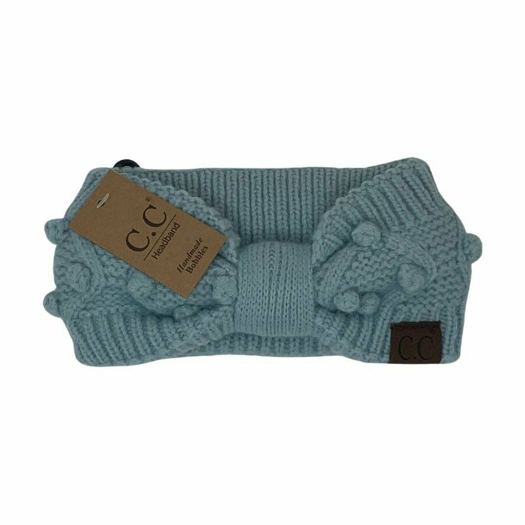 Teal knitted headband with brown label on a white background